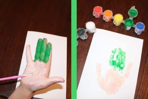 Elf Handprint card - child's hand is painted with green on the 3 middle fingers and beige on the rest of the hand and 2 outer fingers.