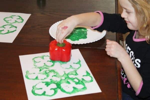 Green pepper shamrock stamping - child is using green paint and a pepper to stamp and make a clover for st patricks day