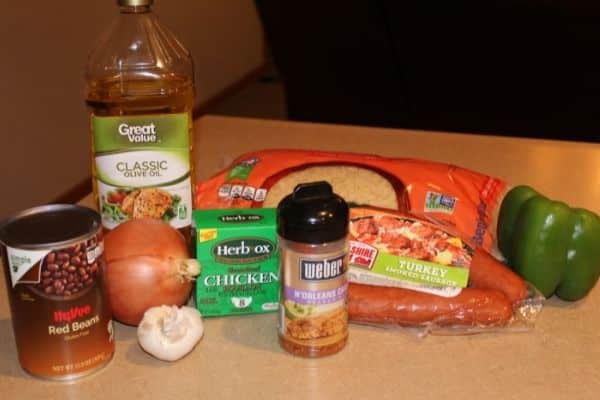 Ingredients for gluten free red rice and beans including: red beans, herb-ox, garlic, onion, bell pepper, kielbasa, cajun seasoning, long grain rice, olive oil