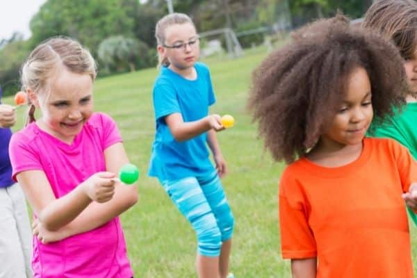 Kids doing a spoon race with plastic easter eggs