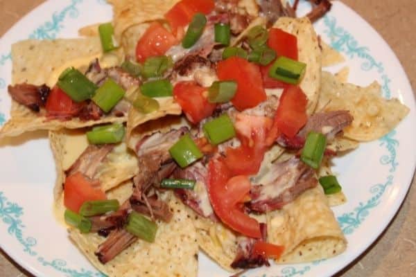 tortilla chips topped with gluten free cheese sauce, brisket, tomatoes, and chopped green onions.