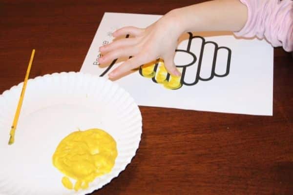 Child making thumbprints on the bee hive printable