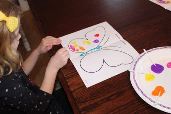 Child painting a butterfly on one side of the line of symmetry