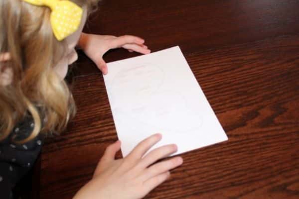 Child folding the paper in half to make a symmetry butterfly painting.