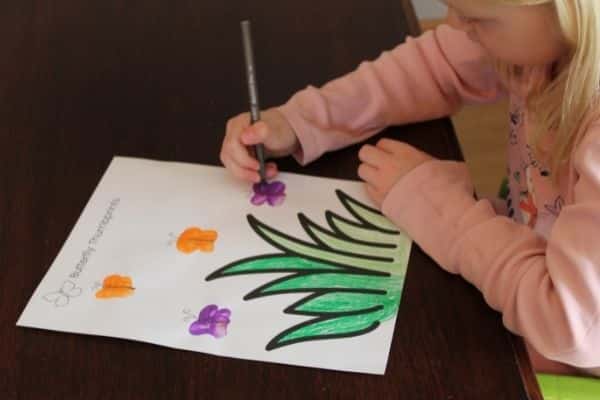 Child drawing the details onto a thumbprint butterfly