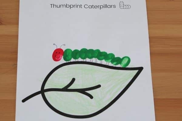 Thumbprint caterpillar craft with legs and face drawn on.