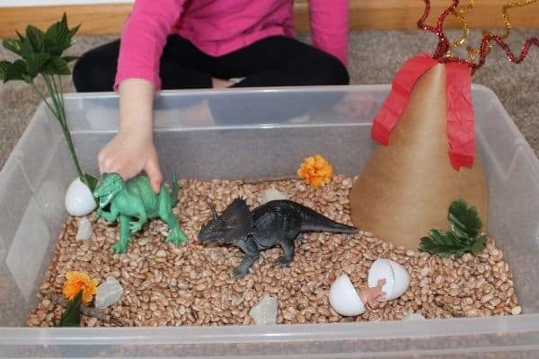 Dinosaur sensory bin - child playing with dinosaur