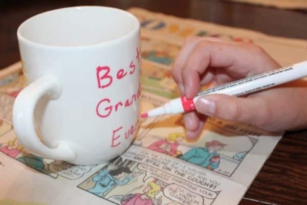 Child writing Best grandma ever on a personalized coffee mug