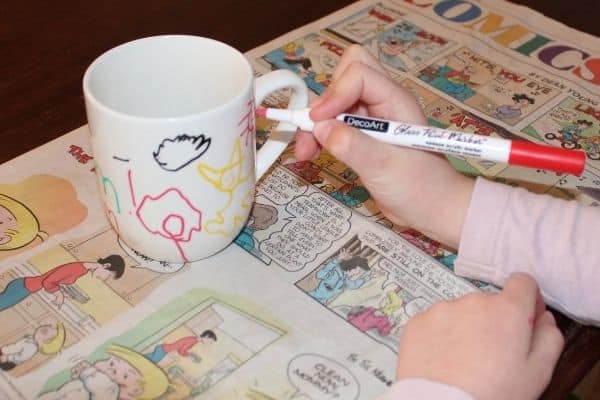 a small child drawing a cat on a custom coffee mug