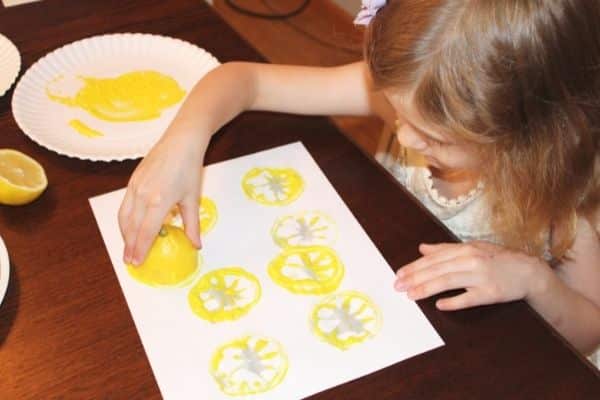 Lemon Stamping process art for preschoolers - child using yellow paint to stamp a lemon onto a page