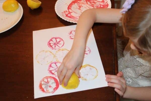 lemon stamping - child using pink paint to stamp a lemon