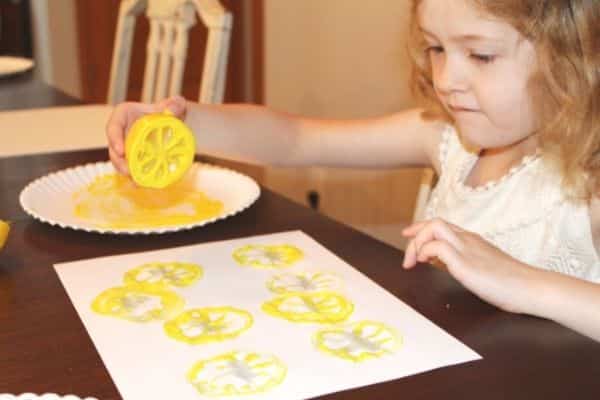 girl using a lemon to stamp onto a page 