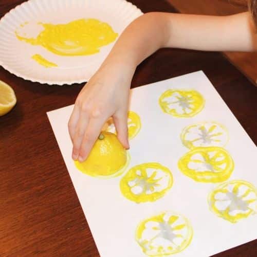 lemon stamping process art for preschoolers, child stamping with a lemon with yellow paint