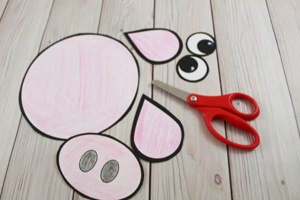 Cutting out the pig paper bag puppet template with scissors