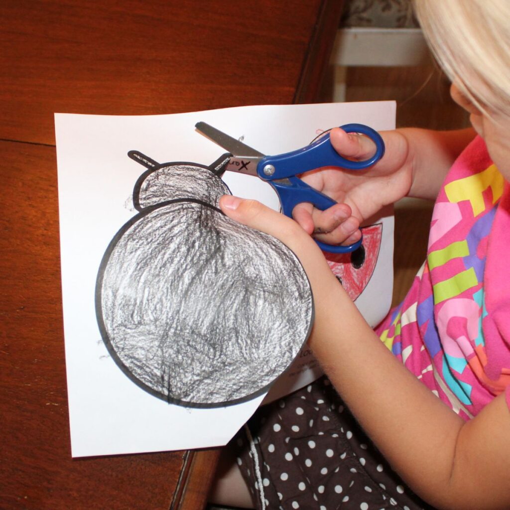 child cutting out the ladybug template