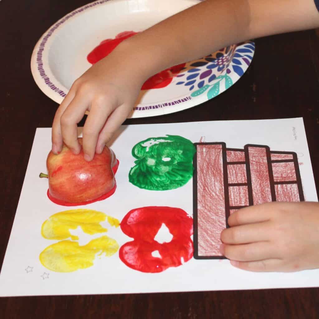 child apple stamping onto an apple basket craft for preschool