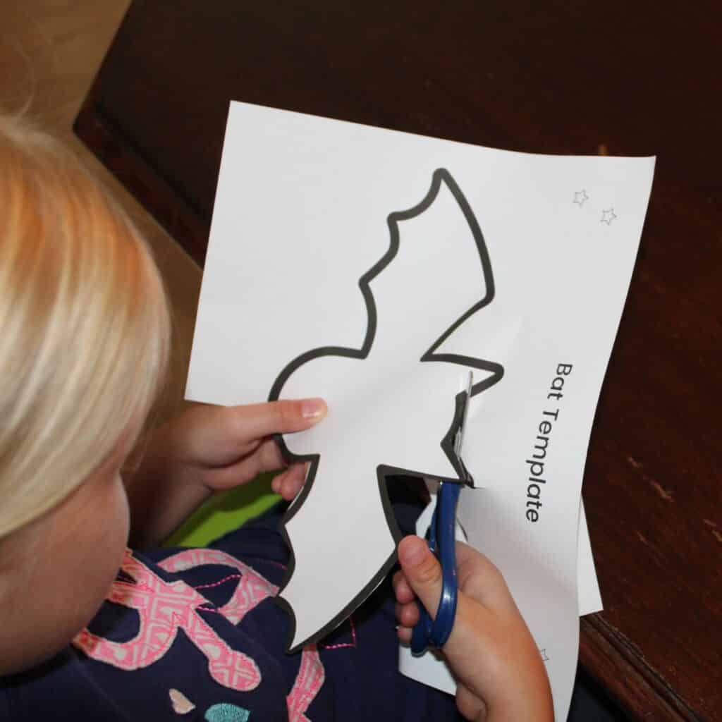 Child cutting out the bat template for the easy preschool bat craft 