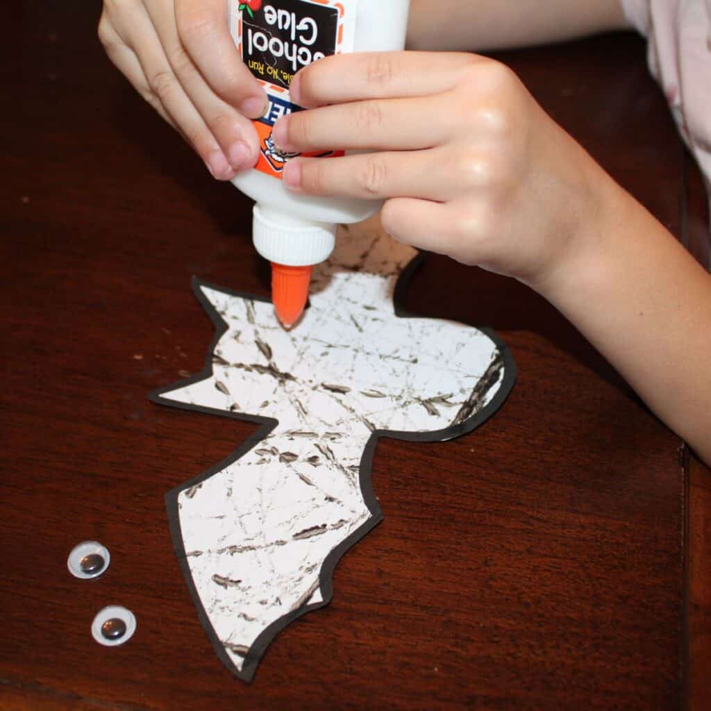 Child gluing eyes to the bat template