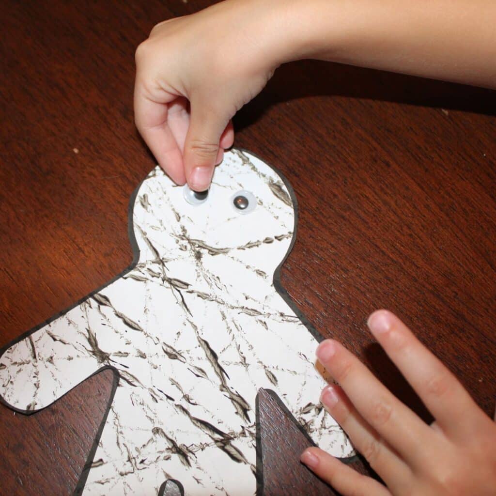 Adding googly eyes to the easy mummy craft preschool