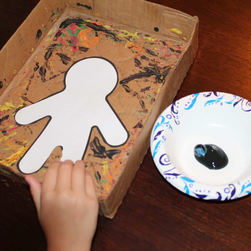 Easy Mummy craft - Mummy template is placed in a box, marble is placed in a bowl of black paint.