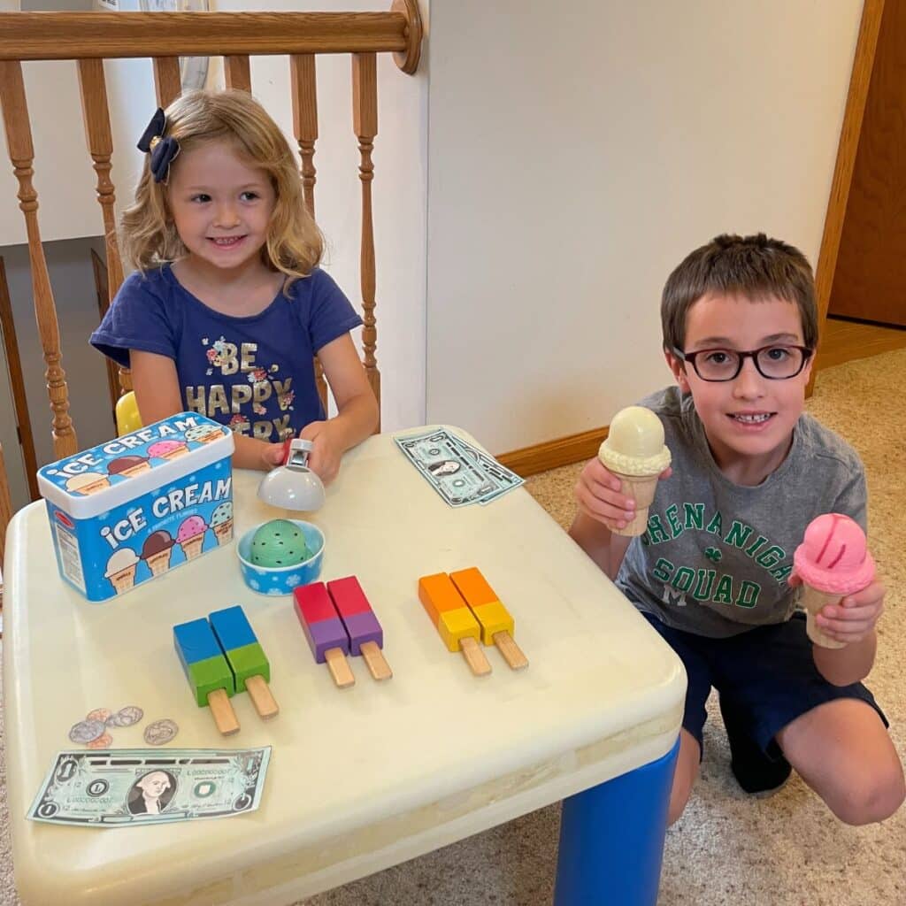 A boy buys ice cream from a pretend ice cream stand paying with this pretend fake dollar bills.