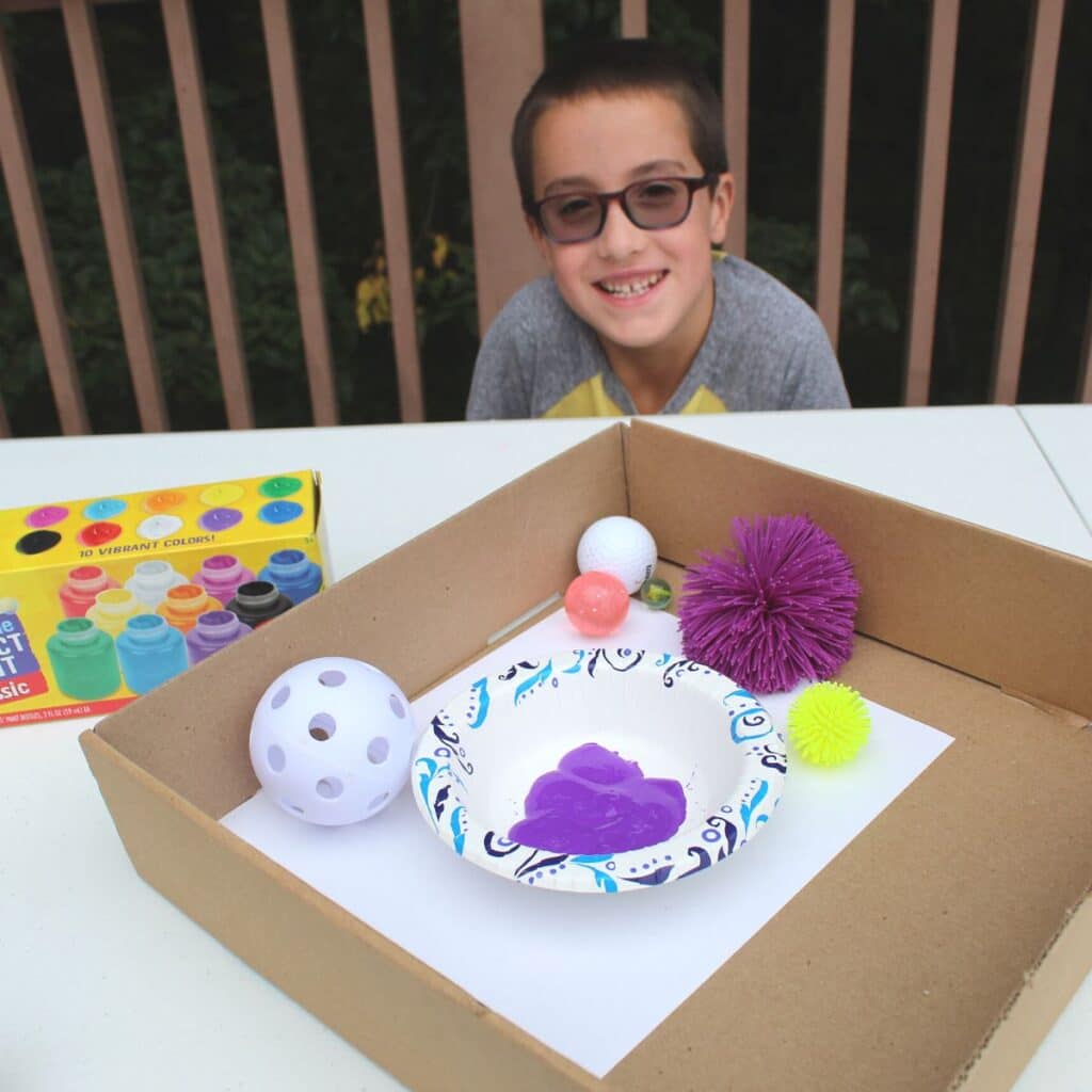 child shown with a box of different balls for ball painting for kids