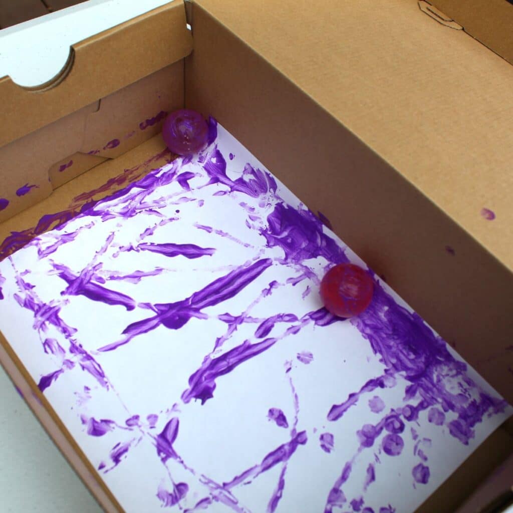 bouncy balls in a box to paint - child has placed bouncy balls into paint and then into a box to paint the page