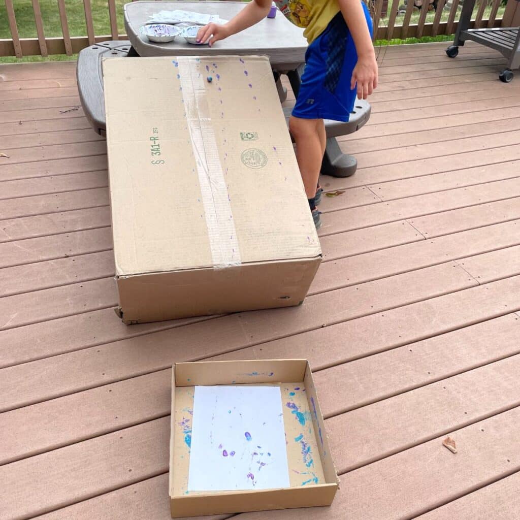 child using a ramp to paint with marbles