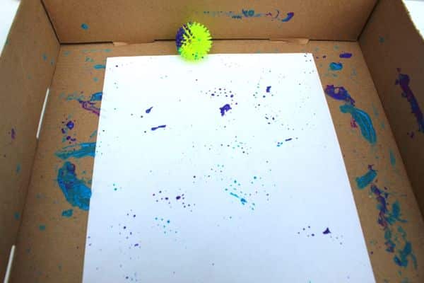 Child using a spiky ball to marble paint - painting with balls activity for kids
