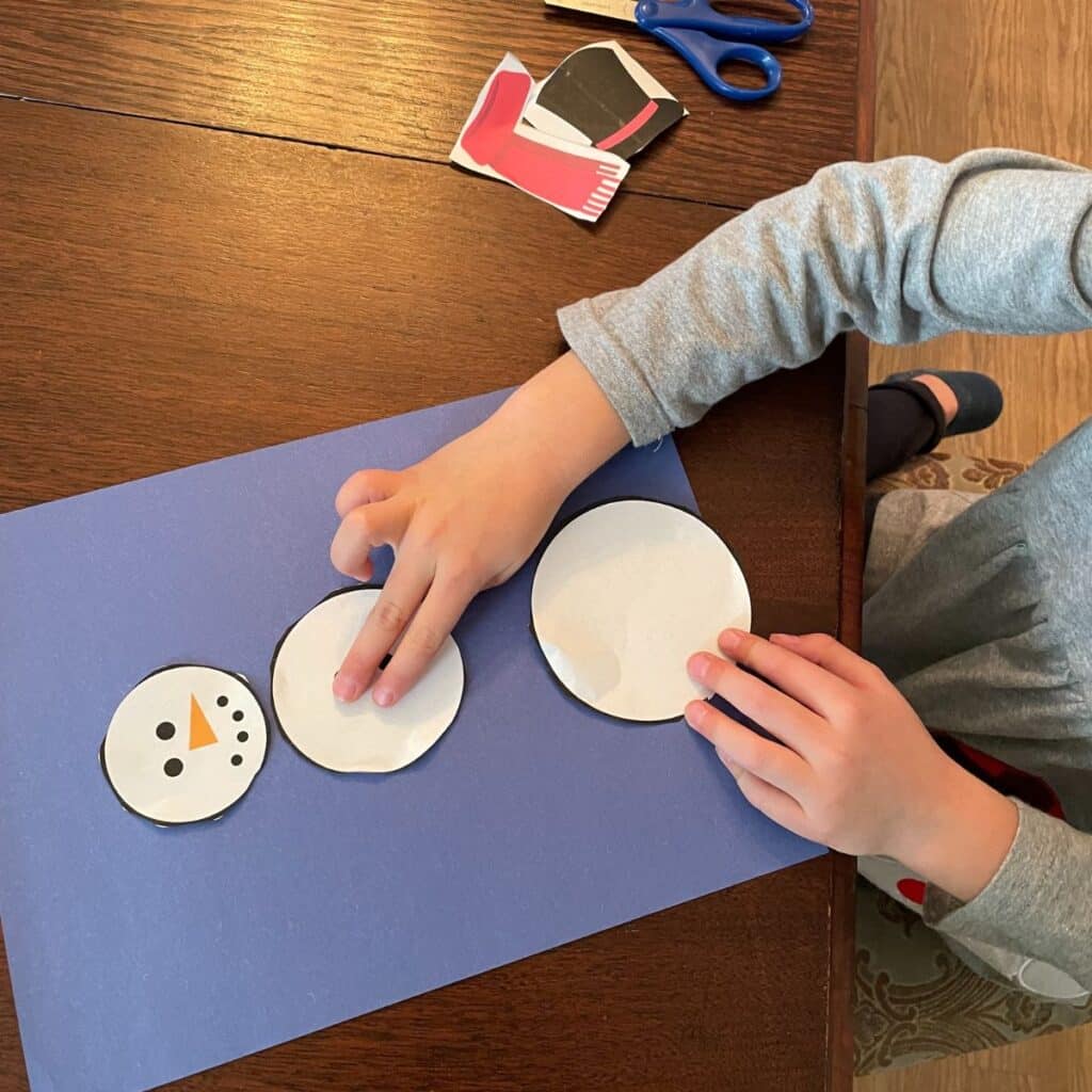 child building a paper snowman