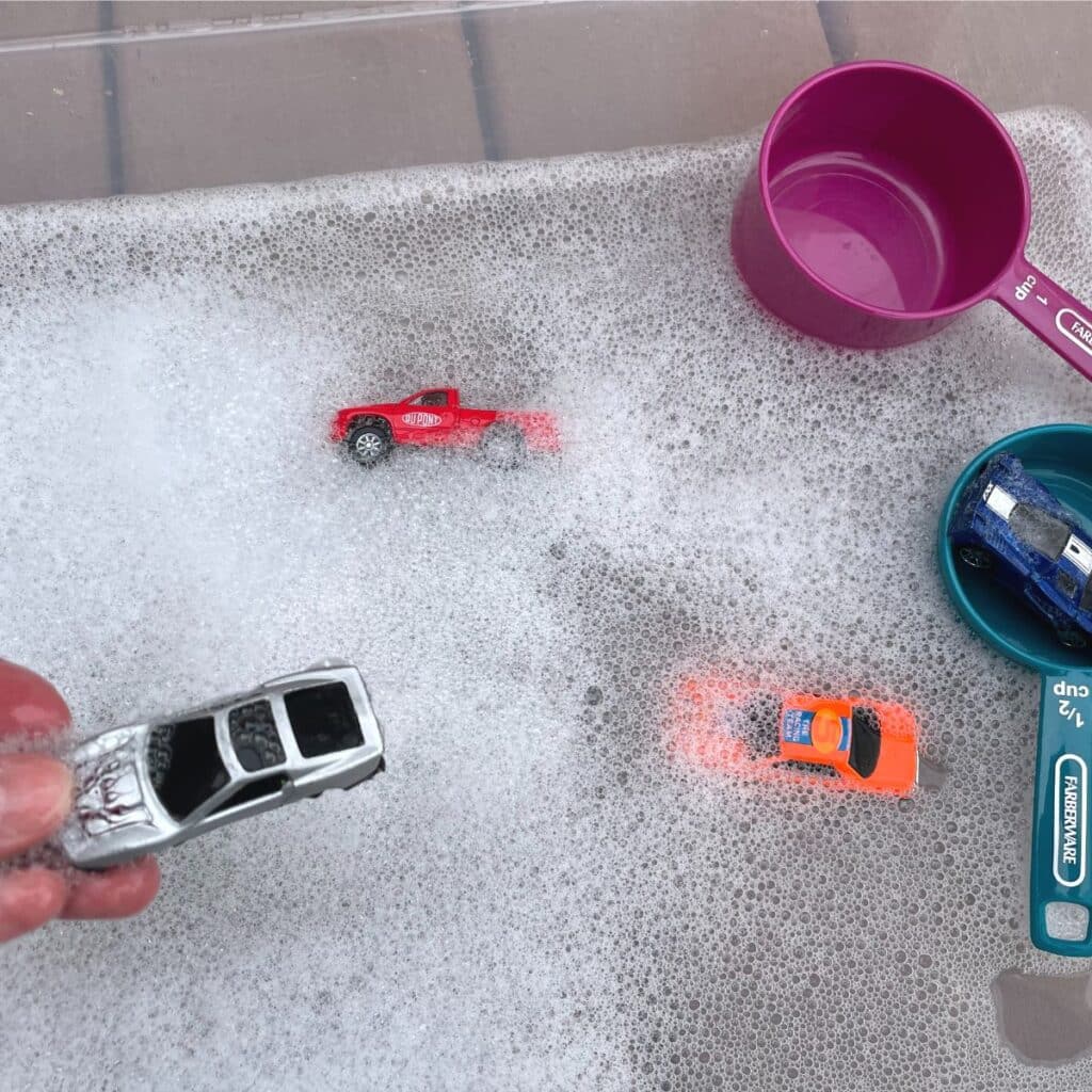 Car Wash Sensory Play - a fun car wash sensory bin idea for preschoolers and toddlers.  Shown:  bubble in water with toy cars, and scoops