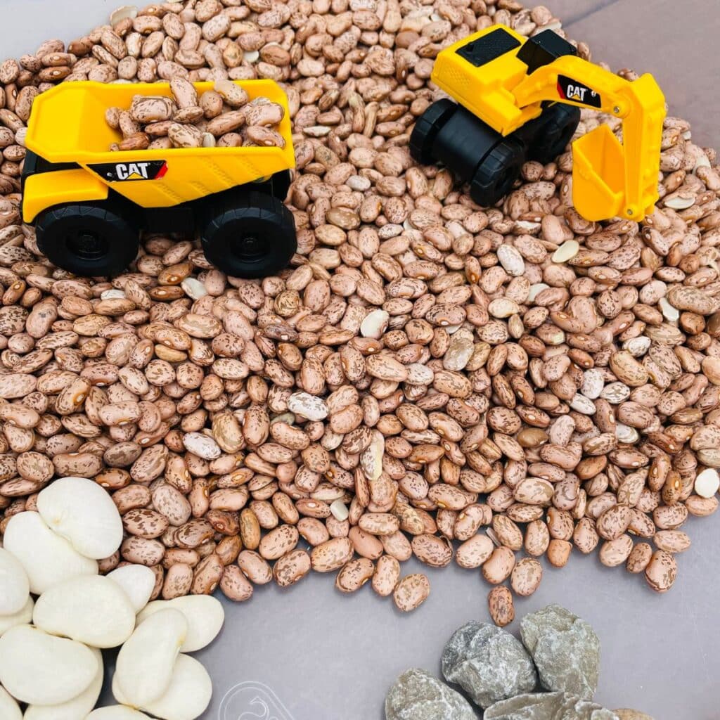 construction sensory bin - a construction site themed sensory activity - contains construction vehicles, beans, rocks,