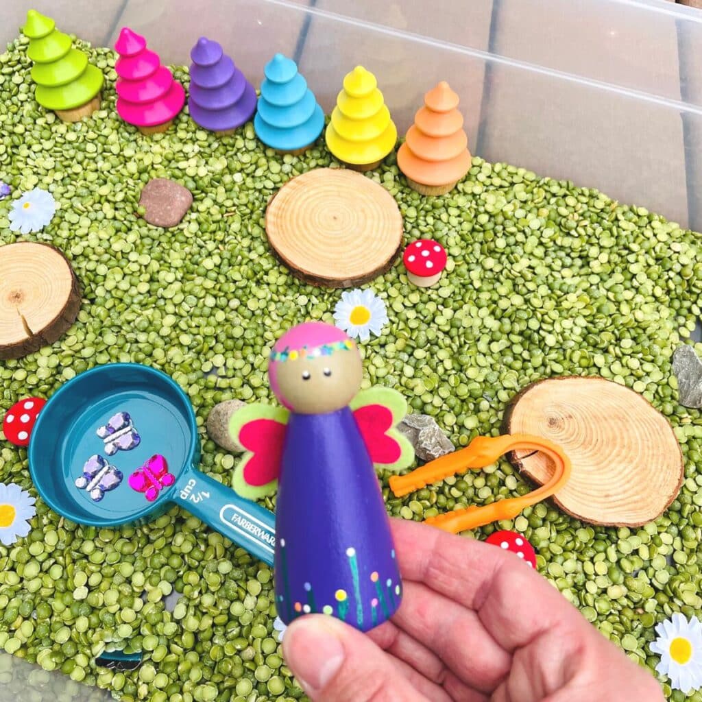 person holding the fairy in a fairy sensory bin