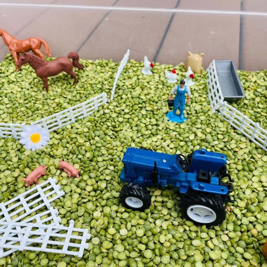 farm sensory bin featuring toy tractor, green split peas, farm animals and more