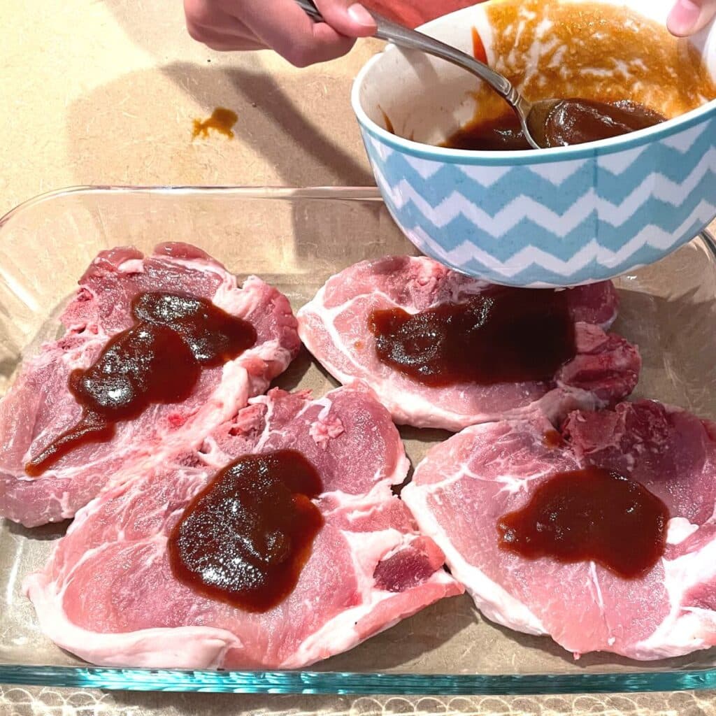 gluten free pork chop being drizzled with sauce