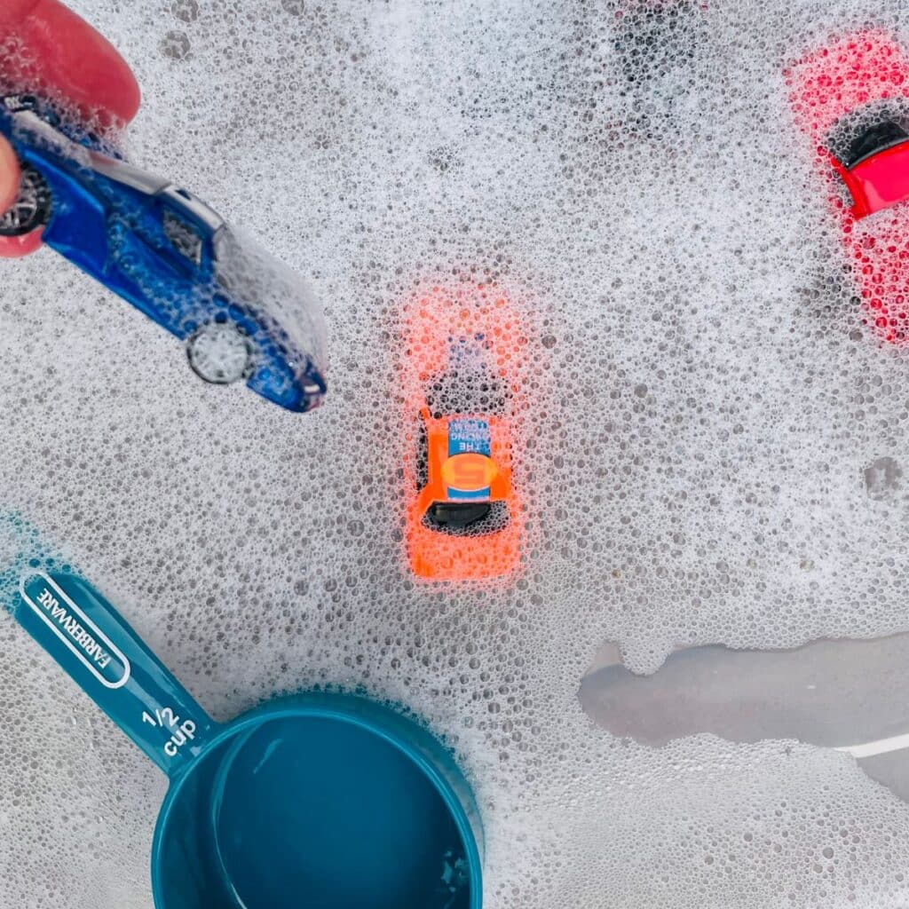 close up of car wash sensory bin - water, bubbles, scoops and cars