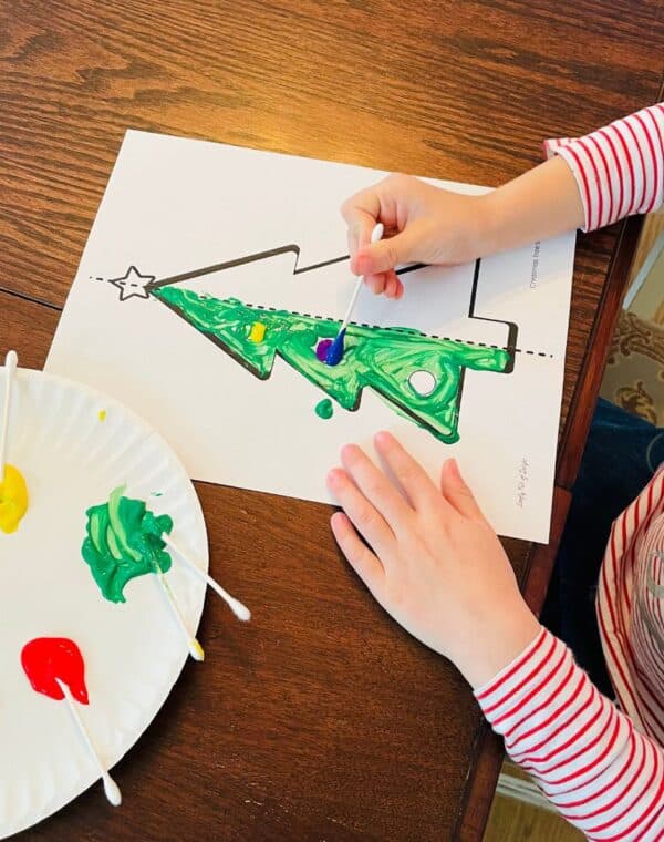 child painting a symmetry Christmas tree craft - free printable