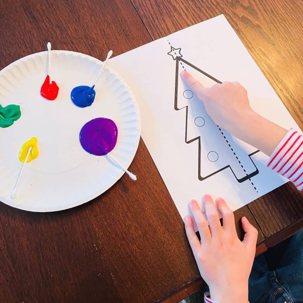 child pointing at the line of symmetry on the Christmas tree symmetry craft