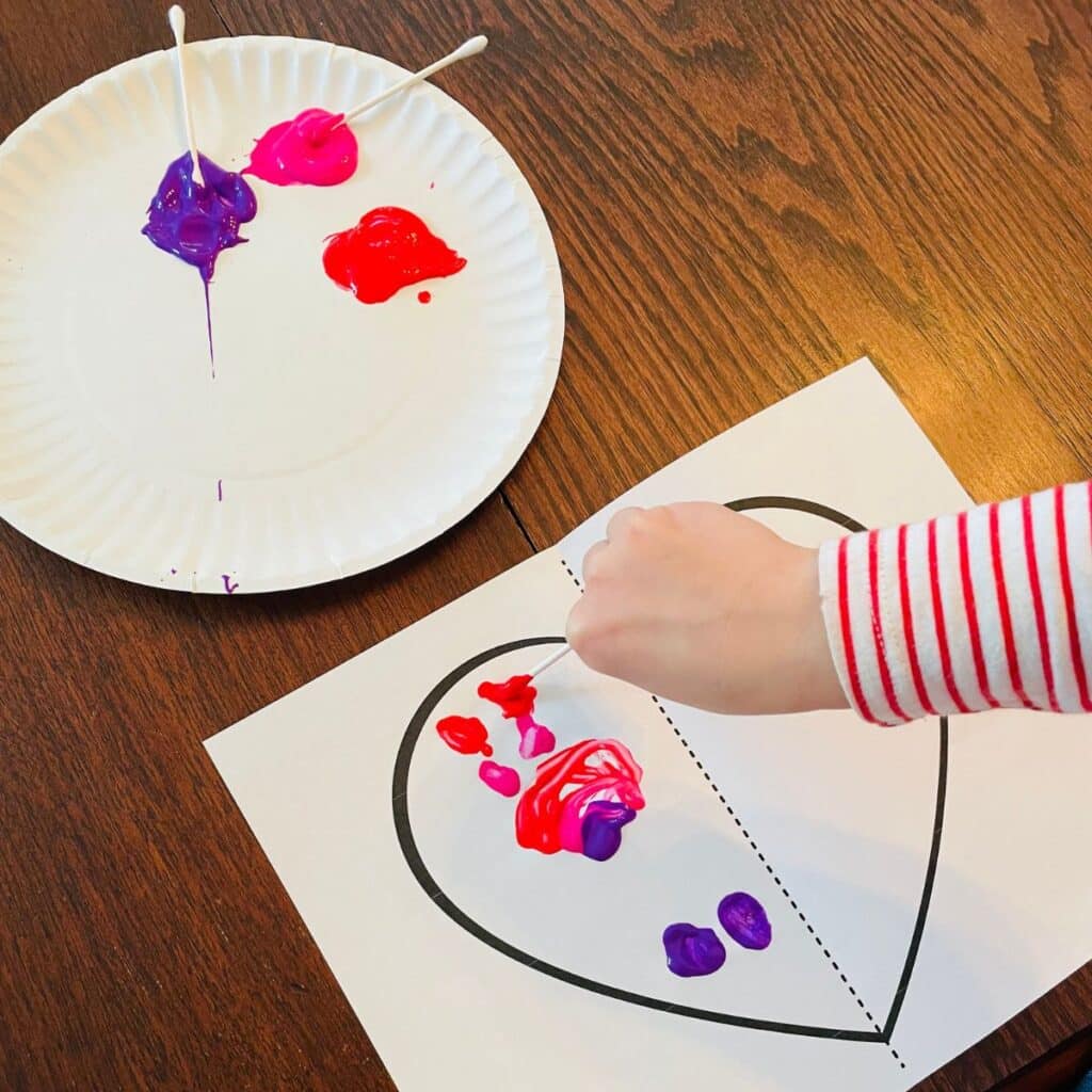 child painting the symmetry heart craft for kids