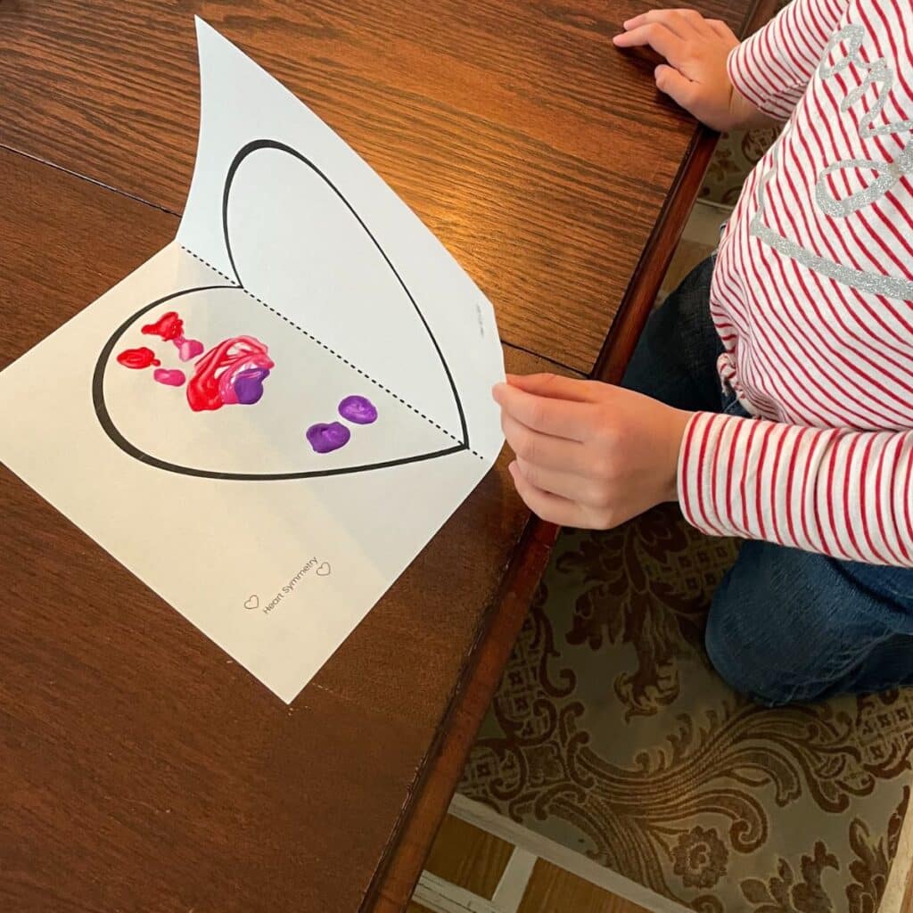 child folding the symmetry heart craft in half