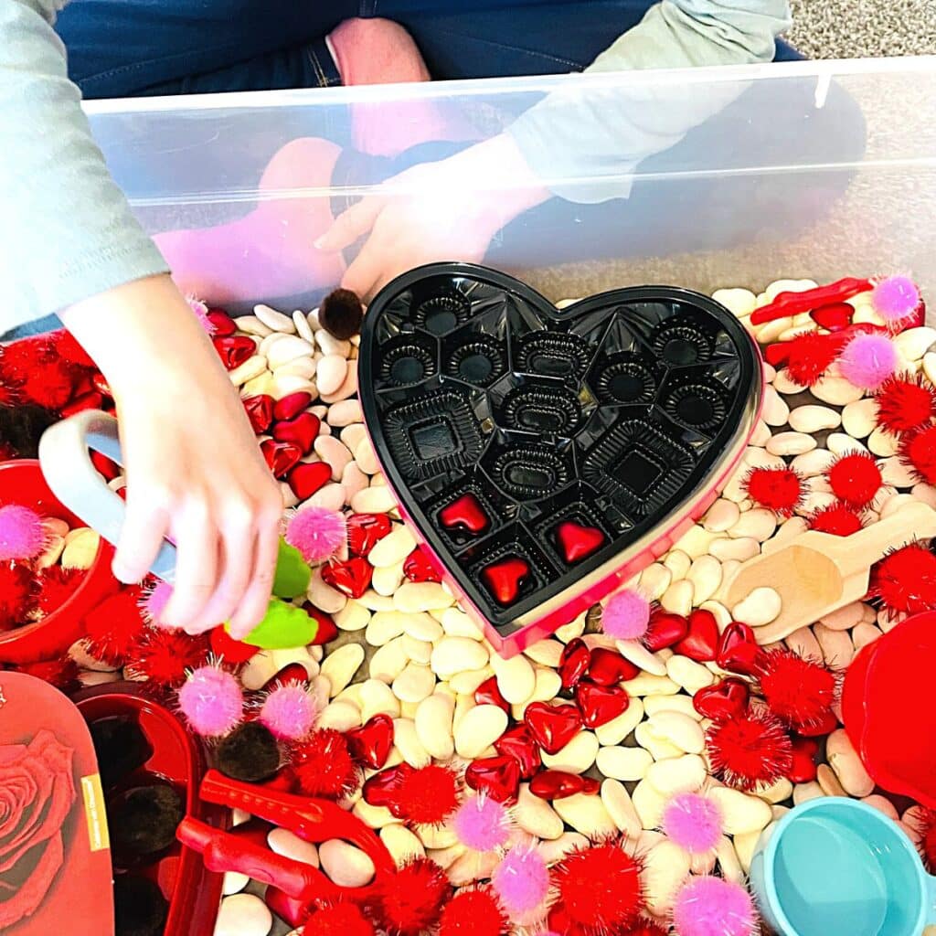 child using tongs for Valentine sensory bin