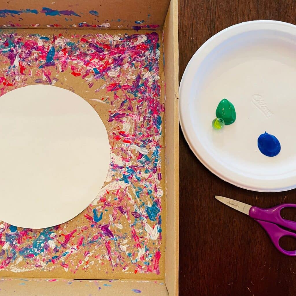 Earth day craft supplies including earth template, box, marble, paint, scissors, and paper plate