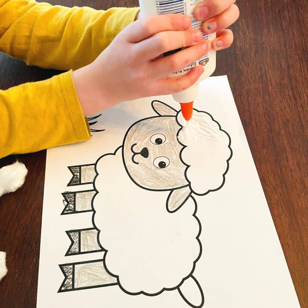 child adding glue to the cotton ball sheep craft