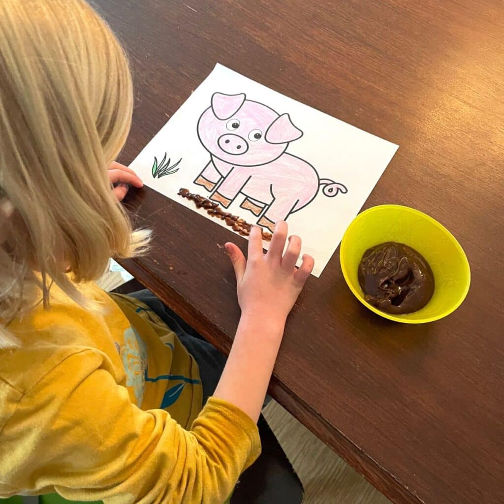 child finger painting with chocolate pudding on a pig printable