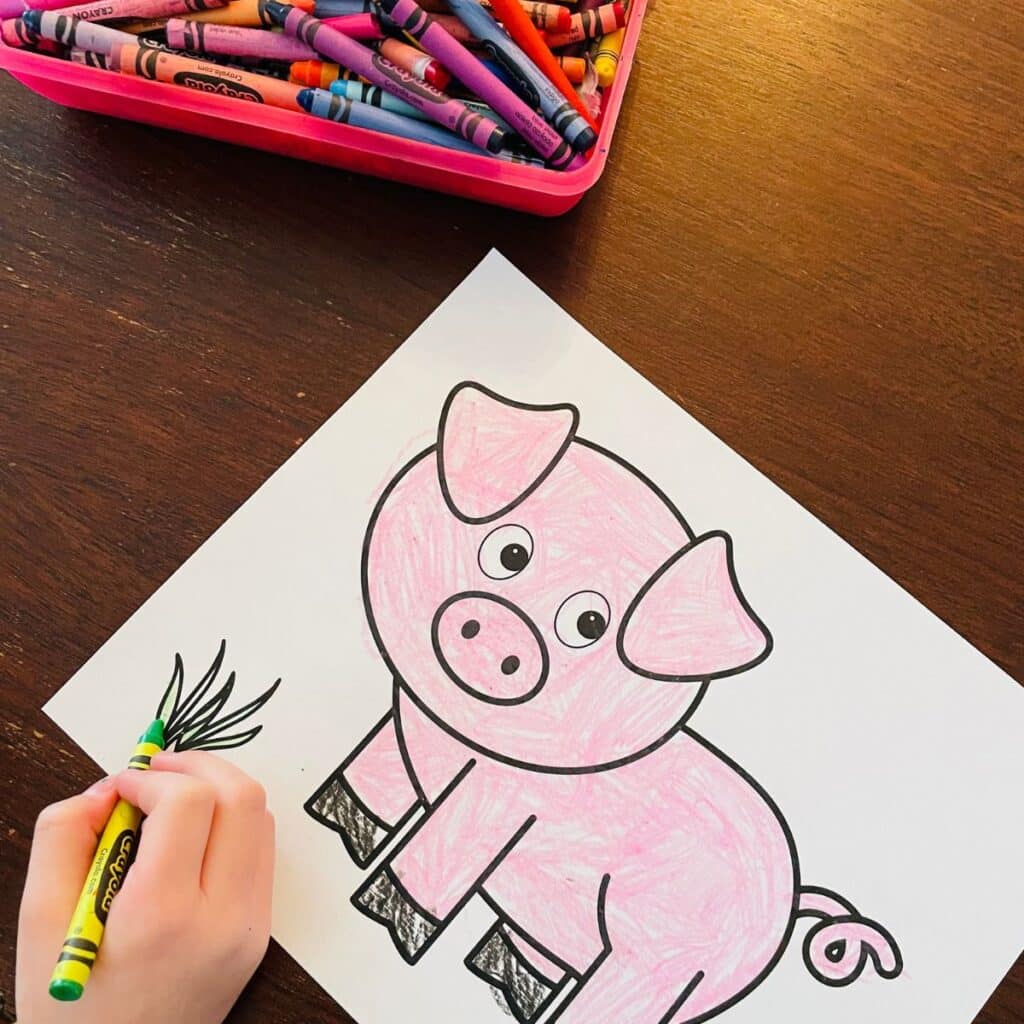child coloring the pig template pink and the plant green