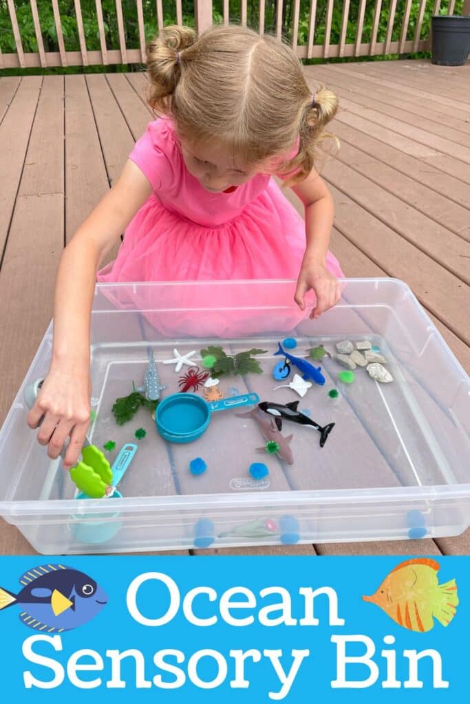 child playing in an ocean themed sensory bin - using tongs to pick up sea animals