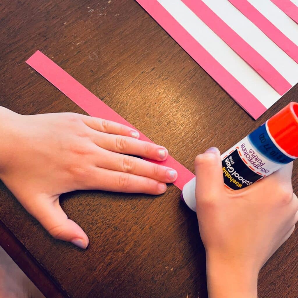gluing down the red stripes onto the handprint flag