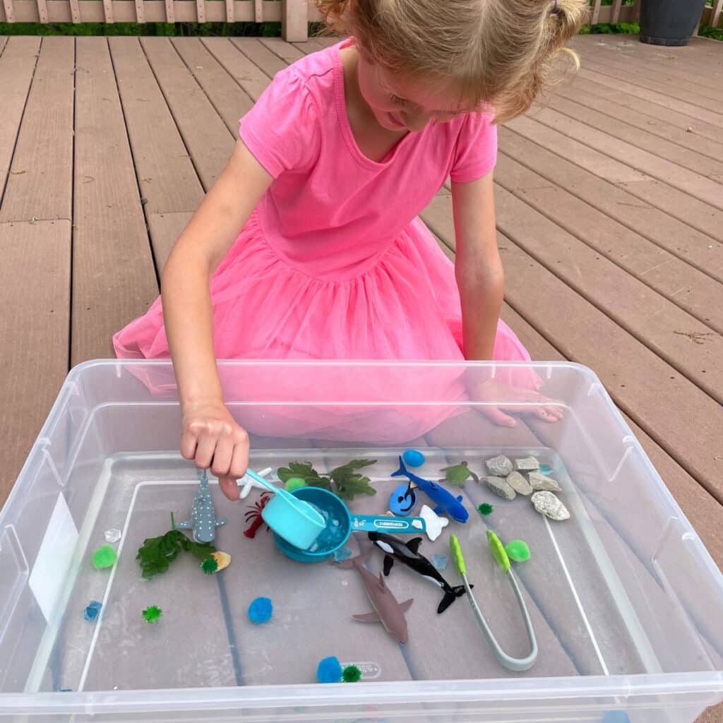 child scooping water in the ocean sensory play idea