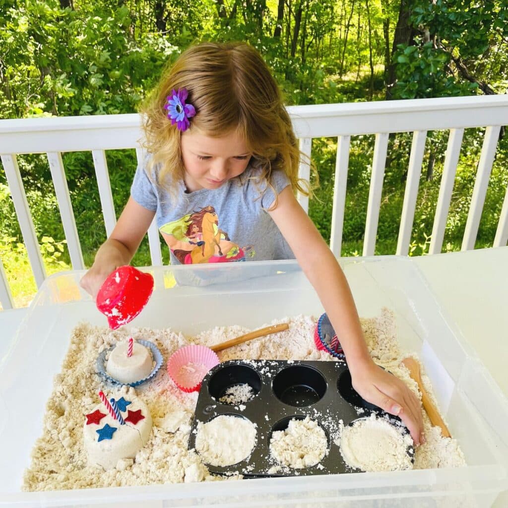child playing in July 4th sensory bin
