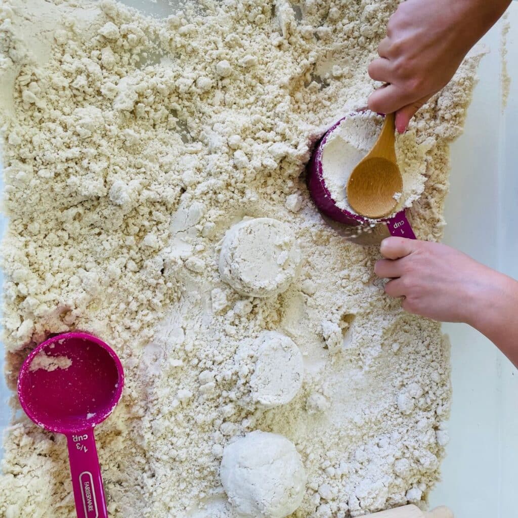 child pressing moon sand into a cup - diy moon sand recipe for sensory play